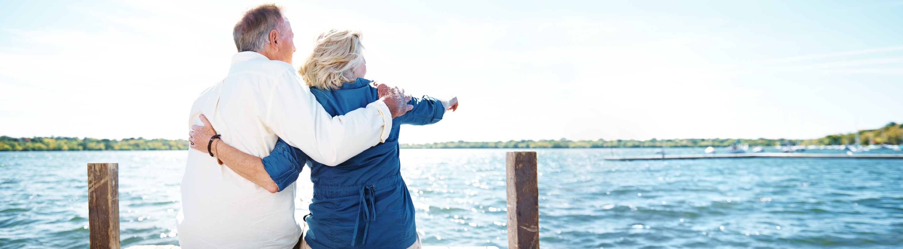 Two older adults sitting on pier at a lake